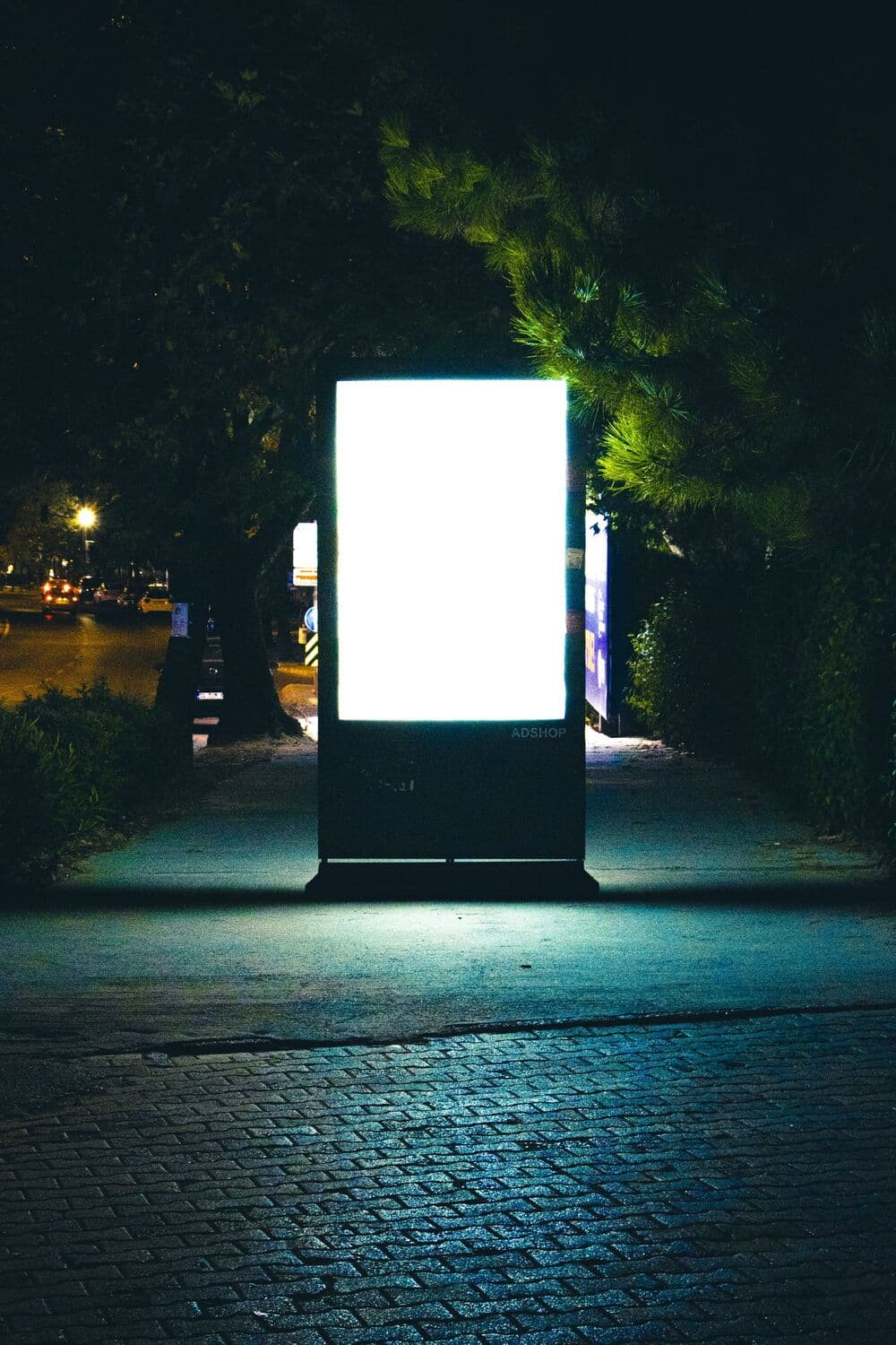 Caisson lumineux publicitaire sur un trottoir, de nuit