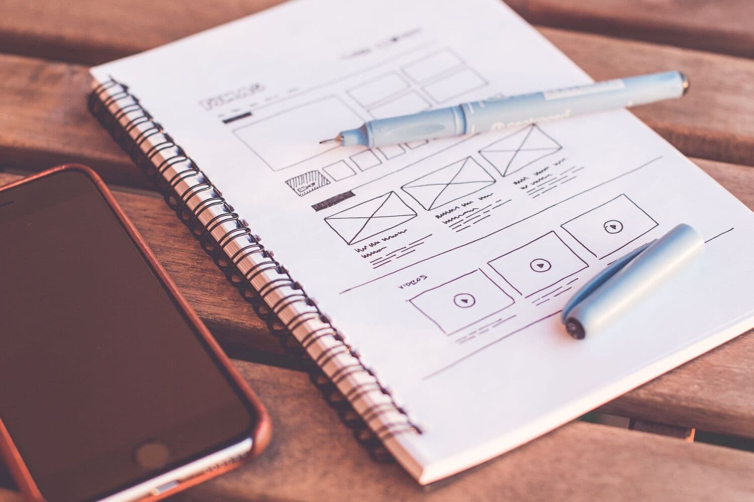 Carnet de wireframes d'une application, posé à côté d'un smartphone