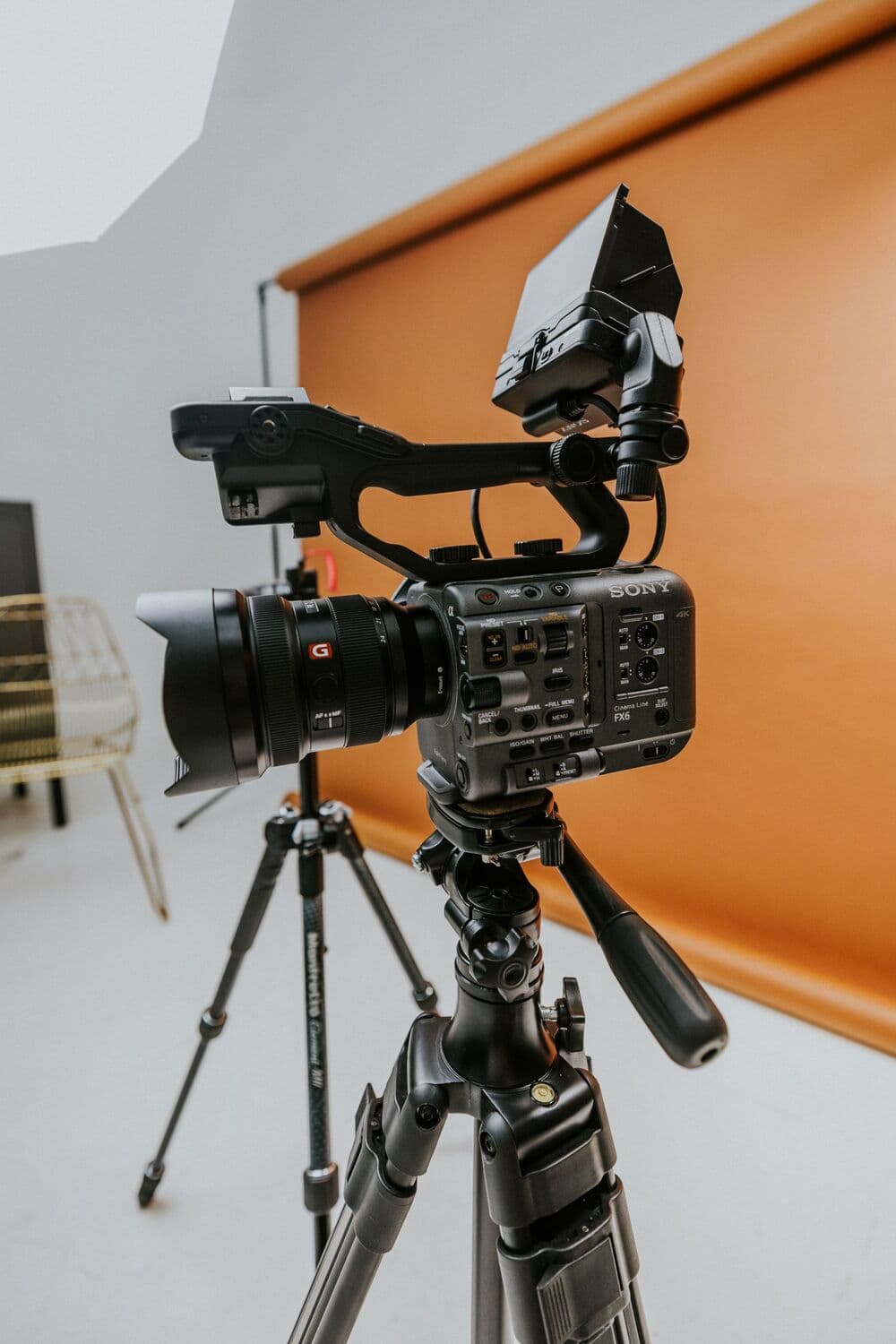 Caméra de cinéma sur un trépied, devant un fond orangé